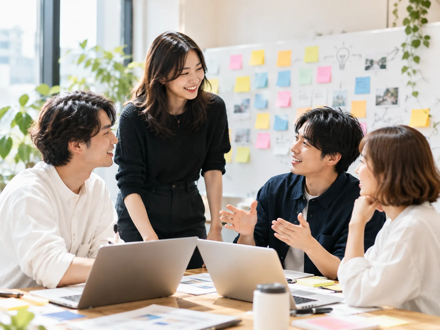 付箋の貼られた壁の前で話し合う4人（イメージ）